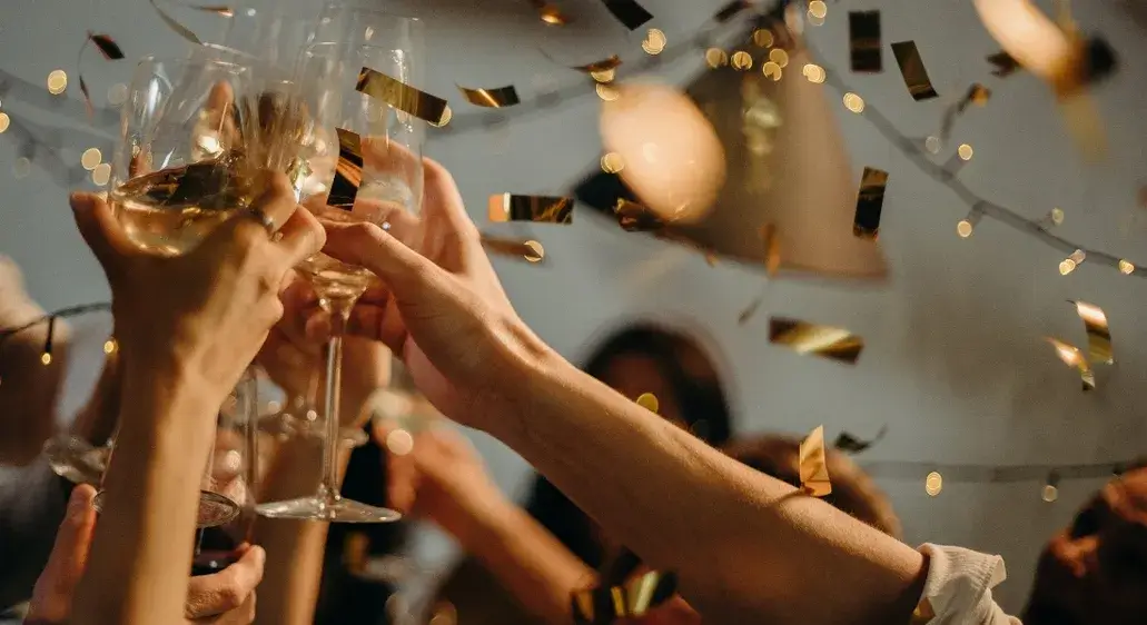 People toasting with champagne glasses during a festive holiday celebration with confetti